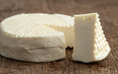 Head and slice of feta cheese on a wooden background. Selective focus.