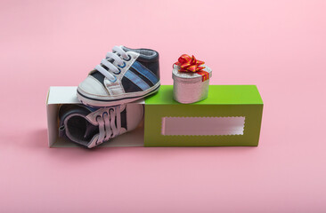 Mockup of children's shoes. Close up of a gift box and gumshoes for a newborn on a colored background. A gift to father