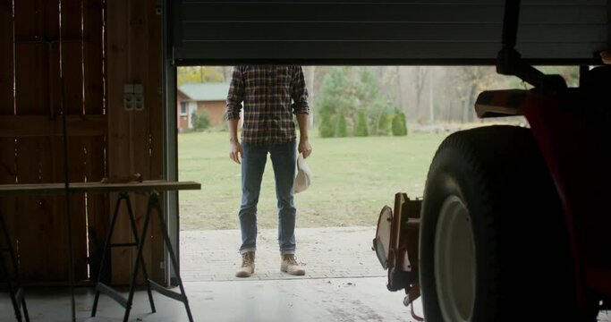 A man walks into an indoor garage approaching a tractor