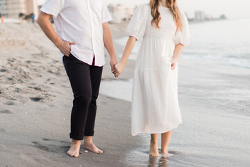 Fototapeta premium Young Couple Holding Hands while walking on the beach in Florida