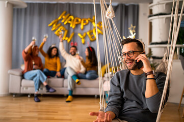 Young man calls a friend to a house party over his phone.