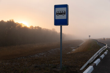 Bus stop sign near highway. Foggy early morning at a highway.