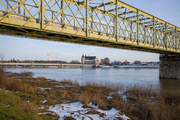 The town center of Sully sur Loire seen from the pedestrian bridge under the snow in Europe, in France, in the Center region, in the Loiret, towards Orleans, in Winter, during a sunny day.