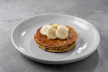 Banana oat pancakes topped with sliced ​​bananas and honey.