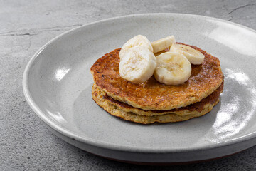 Banana oat pancakes topped with sliced ​​bananas and honey.