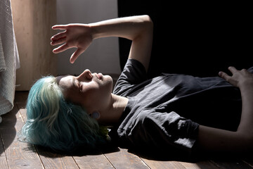 Fototapeta premium young female lying on floor at home, sunlight falls on face. thoughtful lady in contemplation looking up, covering eyes closing from sunlight. problems, human emotions, stress, lifestyle concept