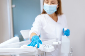 Nurse in protective gloves sanitizing dental chair - obrazy, fototapety, plakaty