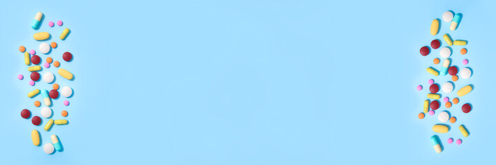 Banner made with assorted multicolored medicine pills, capsules and tablets on blue background with copyspace for your text. Immune system vitamins and supplemets. Dietary bio supplements