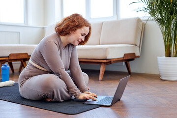 Young chubby redhead woman preparing for an online fitness class, caucasian fat overweight female...