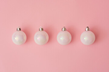 Christmas baubles laid on pink backgorund in a row. Winter holidays flat lay concept.