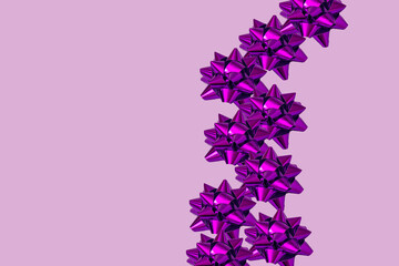 Neon violet gift decorations laid out on pink background. Christmas and New Year present and greeting card idea. Minimal concept.