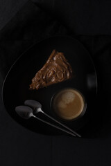 Overhead view of a delicious chocolate cake slice with frosting at the top next to a cup of coffee...