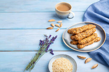 Crumble cookies with seasme and almonds on ceramic plate with cup of coffee on blue wooden background. side view, copy space.