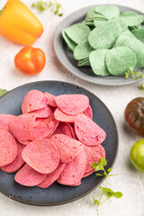 Green and red potato chips on gray concrete background. Side view, close up, selective focus.