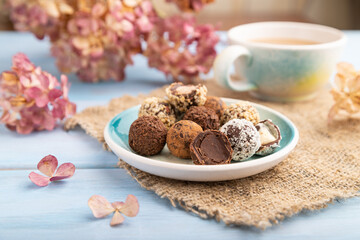 Chocolate truffle candies with cup of coffee on a blue wooden background. side view, close up, selective focus.