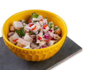 a yellow bowl with ceviche over slate stone isolated on white background