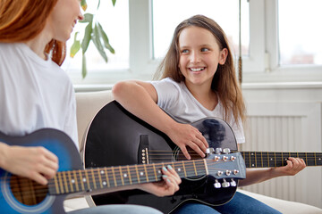 Learning to play the guitar. Nice Female teacher explains to child the basics of playing guitar in...