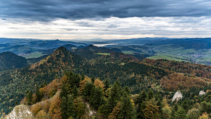 Krajobraz gór porośniętych drzewami w czasie jesieni na tle nieba pokrytego "cięzkimi" chmurami