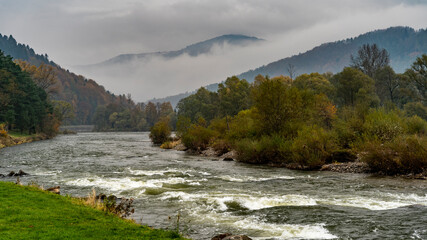 Widok na rzekę Dunajec, otoczona wzgórzami z mgłą w tle