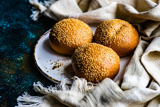 Three fresh bread rolls with sesame seeds on a plate