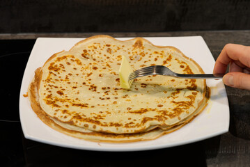 Golden pancakes with butter on a white plate. Isolated black background. close up