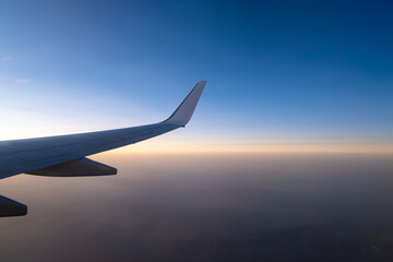 Obraz premium flying and traveling, view from airplane window on the wing on sunset time