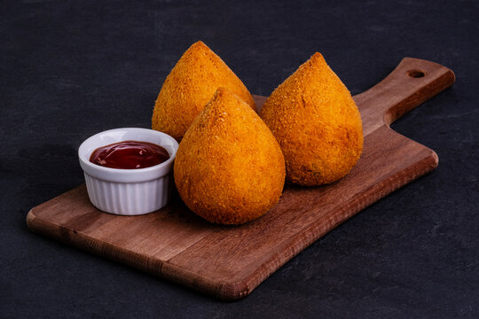 traditional fried coxinha on a wooden board over slate stone