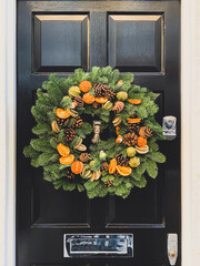 Christmas mood: festive christmasy themed winter natural wreath on a black wooden door. Wreath...