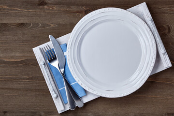 Empty ceramic white plate with cutlery on a napkin