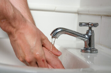 closeup on white male hands being washed at a toilet sink