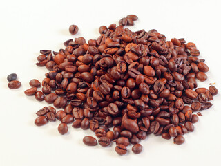 Coffee beans isolated on white background. Pile of roasted coffee beans scattered on white table.