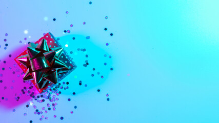 Neon Christmas winter background. Xmas gift box with shine lights. Holiday decoration on neon abstract gradient backdrop. Happy new year copy space. © Maksym