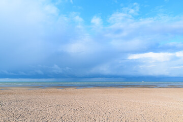 Fototapeta na wymiar The storm over the sandy beach in Europe, France, Normandy, Ouistreham, in summer, on a sunny day.