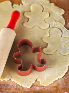 Gingerbread man cookie cutter and rolling pin on cookie dough