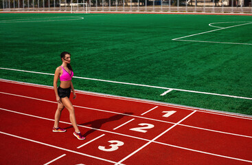 Obraz premium Ready, Set, Go. Young athletic fit hot healthy woman at the sports track at the stadium is about to run a race at the running competition.