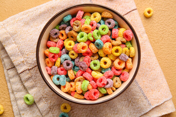 Bowl of colorful cereal rings on color background