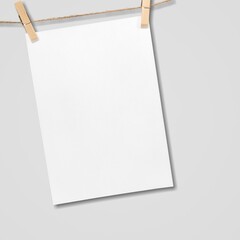 Paper hanging on rope with wooden clothespins on background