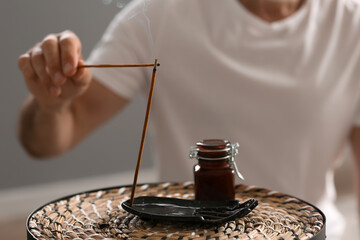 Mature man with incense sticks at home, closeup