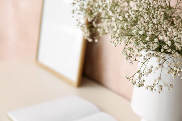 Vase with gypsophila flowers on shelf near pink wall, closeup