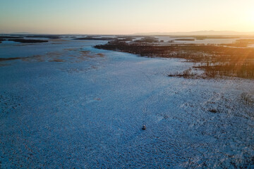 View from above. Snowy expanses of the Jewish region of Russia. The off-road vehicle of the reserve inspectors is driving through a snowy swamp.