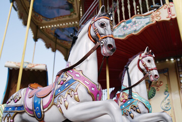 Fototapeta na wymiar Horses on a carnival Merry Go Round. Old carousel in a holiday park.