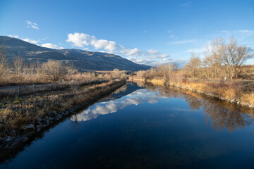 clouds and mountain reflection on a river in a valley in autumn