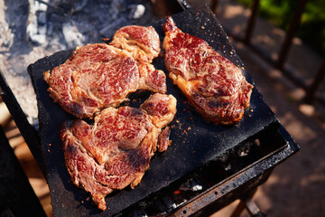 Raw beef burger steak on grill. Cutlet meat placed on grill stone with fire.