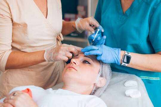 Botox injection into mimic wrinkles on the forehead by a student under the supervision of a master beautician doctor in a cosmetology office. Learning