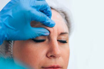 Botox injection in the forehead, probing the injection site by a master cosmetologist