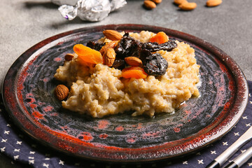 Tasty oatmeal with prunes, dried apricots and almond nuts in plate on grey and white table, closeup