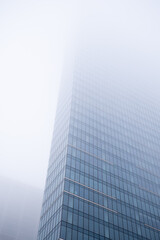 Fototapeta na wymiar Business center in the tower skyscraper in the financial downtown center of the city in the foggy misty day with cover by clouds tops. Financial business abstract architecture concept.