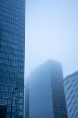 Business center in the tower skyscraper in the financial downtown center of the city in the foggy misty day with cover by clouds tops. Financial business abstract architecture concept.