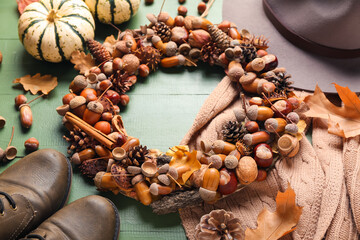 Beautiful acorn wreath and sweater on green wooden background
