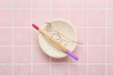 Wooden brush and flower on color background